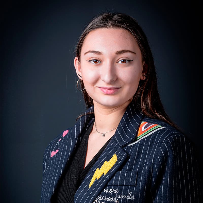 Portrait studio d'une jeune femme en blazer sur fond sombre